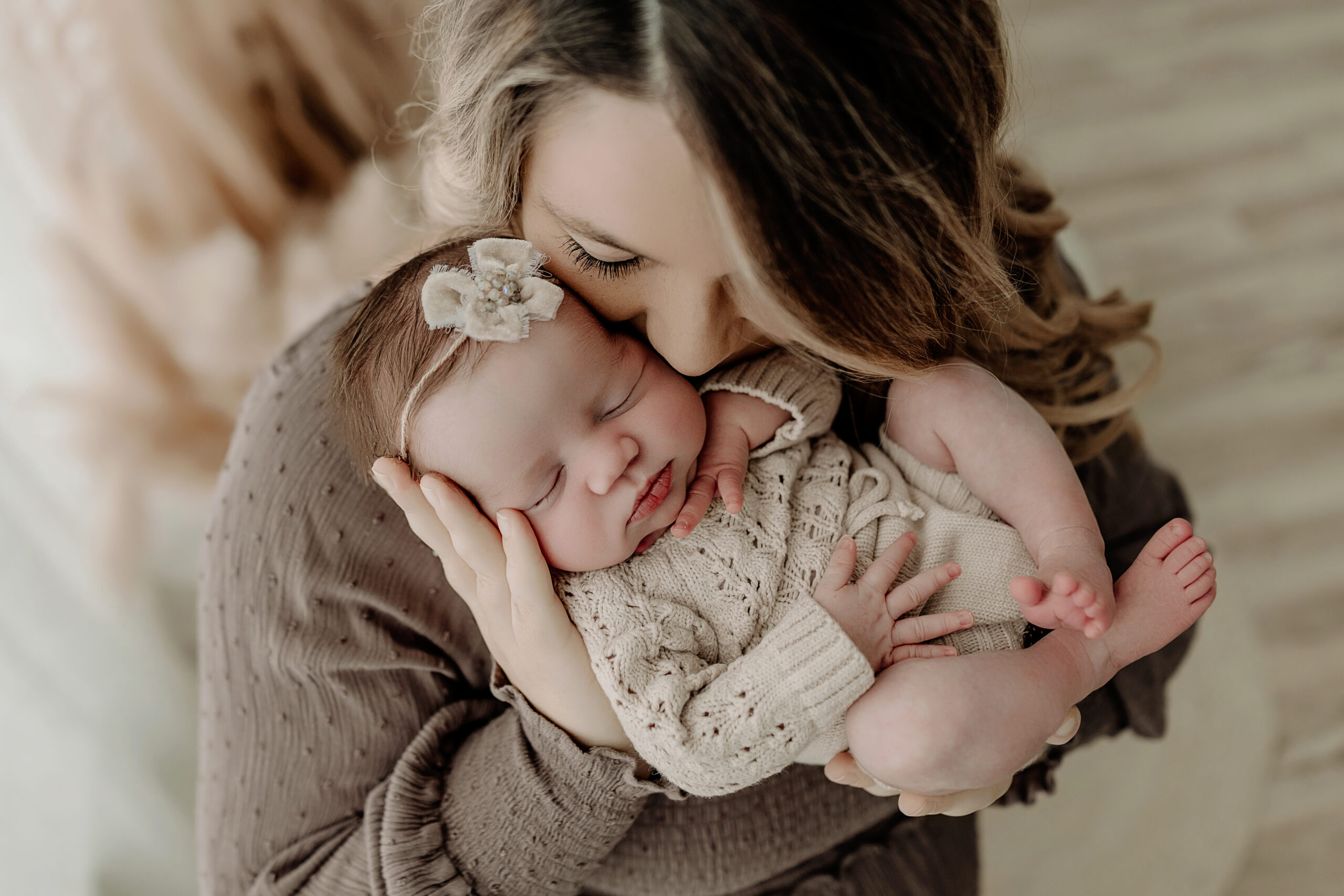 Mom holding newborn baby in natural light studio